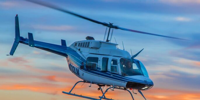 Hélicoptère Bell 206 en vol avec couché de soleil