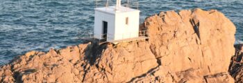 Guernesey : Petit bâtiment blanc sur la côte rocheuse.