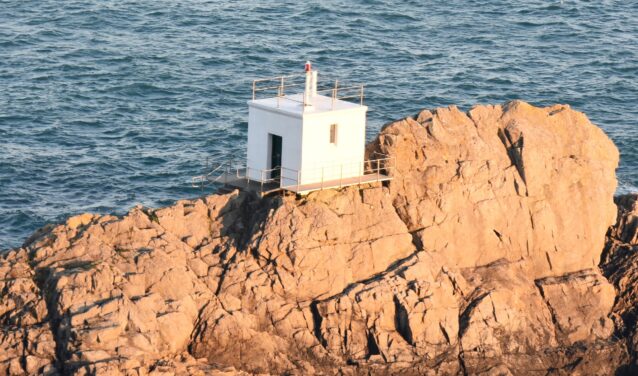 Guernesey : Petit bâtiment blanc sur la côte rocheuse.