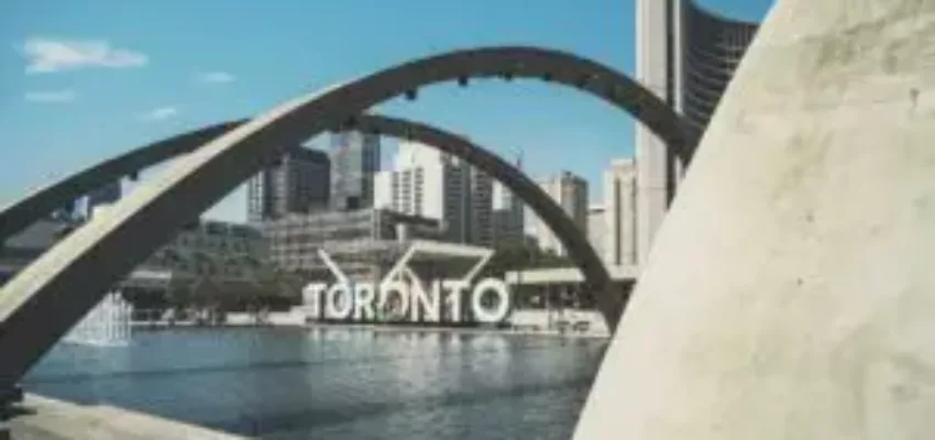 Toronto signe devant les bâtiments sous ciel bleu.
