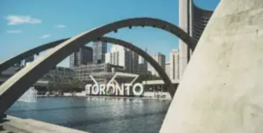 Toronto signe devant les bâtiments sous ciel bleu.